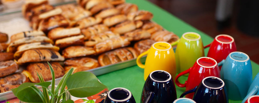 Kaffeetheke mit umgedreht aufgestellten Kaffeetassen und Gebäck auf zwei Blechen